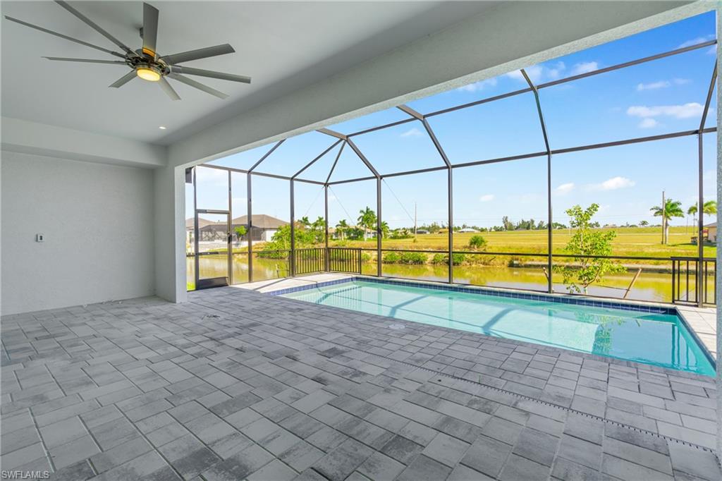 Swimming pool with a sunroom, a ceiling fan, a lanai, a patio area, and a water view