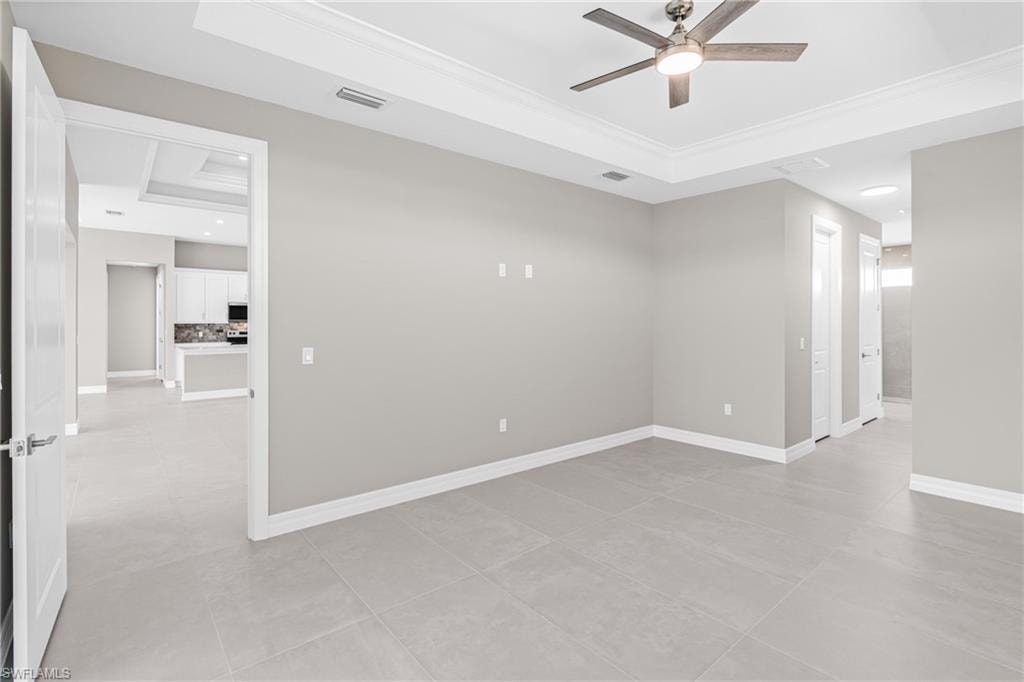 Unfurnished room featuring a raised ceiling, light tile patterned floors, crown molding, a ceiling fan, and recessed lighting