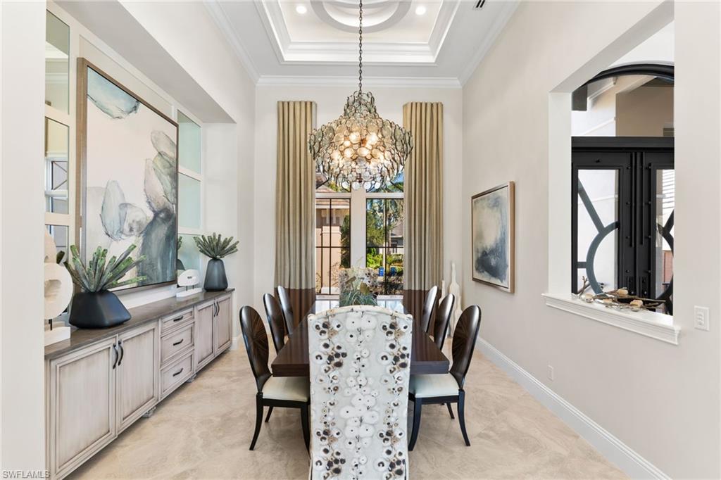 Dining space with a tray ceiling, hanging lights, and ornamental molding