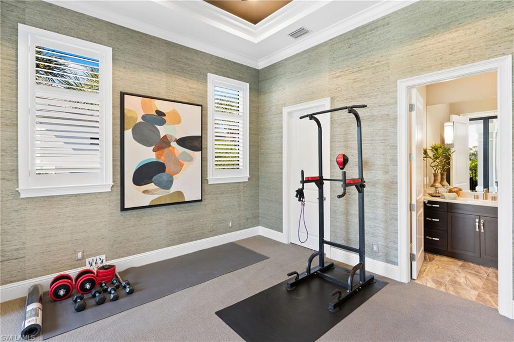 Exercise area with ornamental molding, wallpapered walls, and light colored carpet
