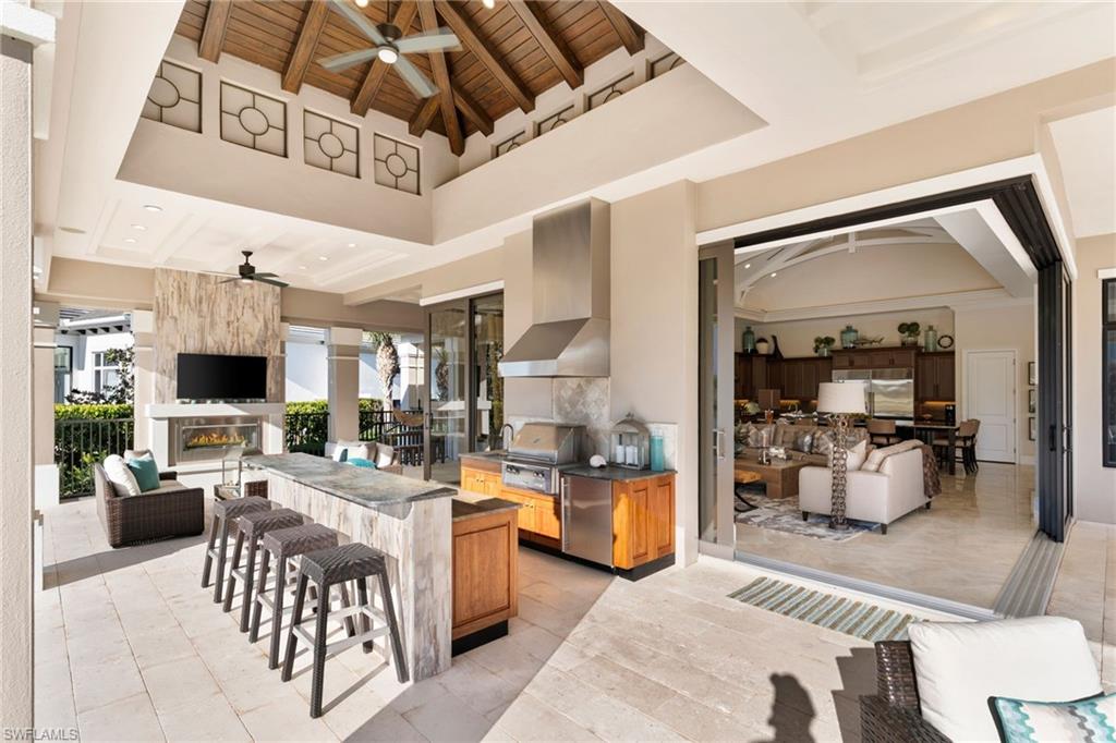 Kitchen with open floor plan, a ceiling fan, a kitchen breakfast bar, and a high wooden beamed ceiling