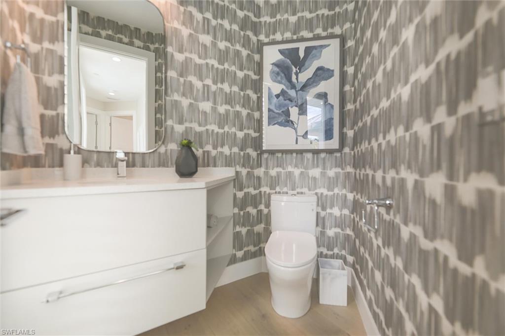 Bathroom with tile walls, hardwood / wood-style floors, toilet, and vanity