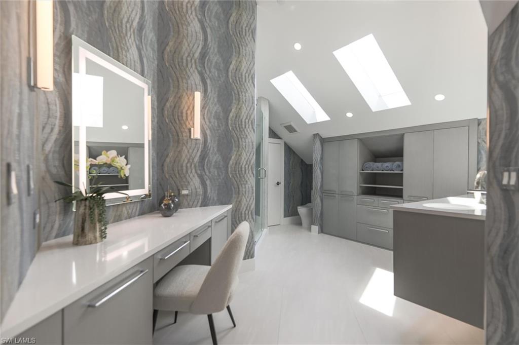 Bathroom featuring tile floors, vaulted ceiling with skylight, toilet, and vanity