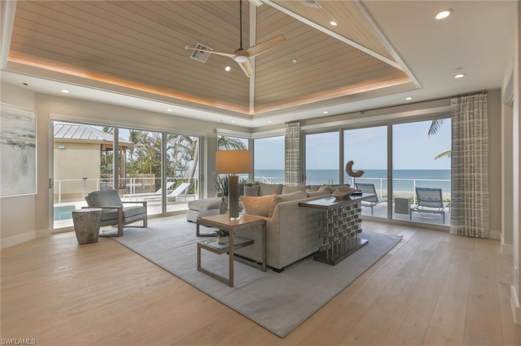 Living room featuring light hardwood / wood-style floors, wooden ceiling, a water view, a high ceiling, and a raised ceiling