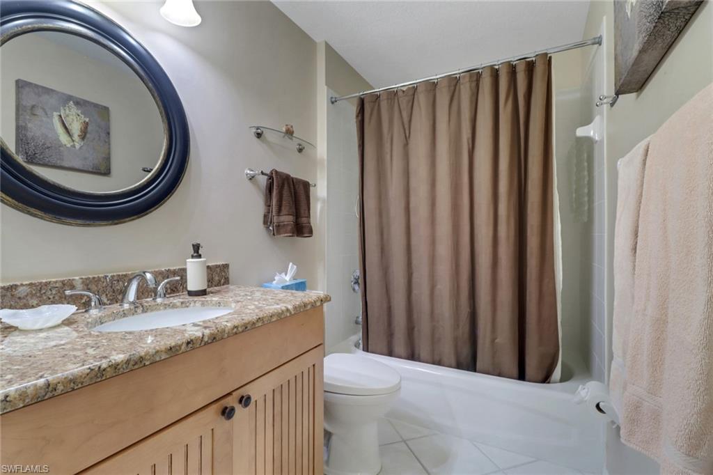 Full bathroom with tile patterned floors, shower / bath combo with shower curtain, vanity, and toilet