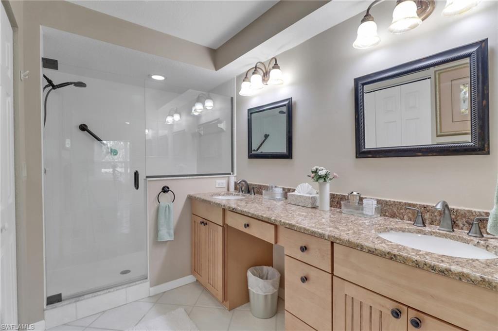 Bathroom featuring tile patterned floors, vanity, and a shower with door