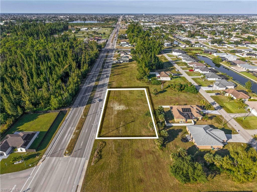 Aerial overview of property's location with property parcel outlined, nearby suburban area, and a nearby body of water