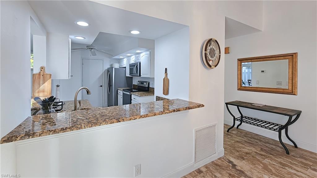 Kitchen with appliances with stainless steel finishes, recessed lighting, white cabinets, dark stone countertops, and ceiling fan