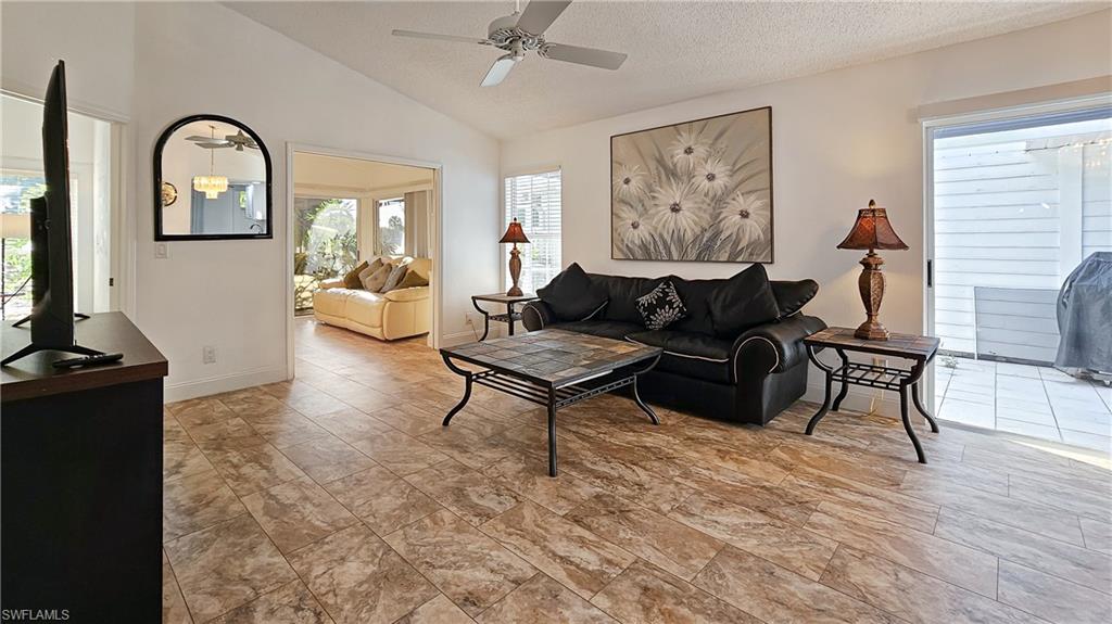 Living room with vaulted ceiling, plenty of natural light, a ceiling fan, and a textured ceiling