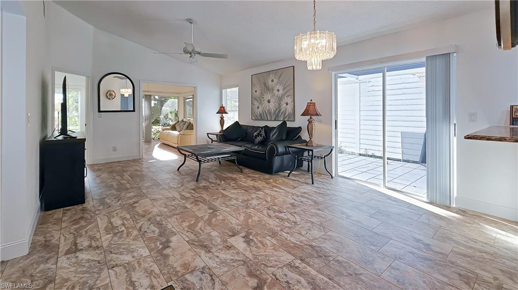 Living room featuring lofted ceiling, healthy amount of natural light, a ceiling fan, and a chandelier