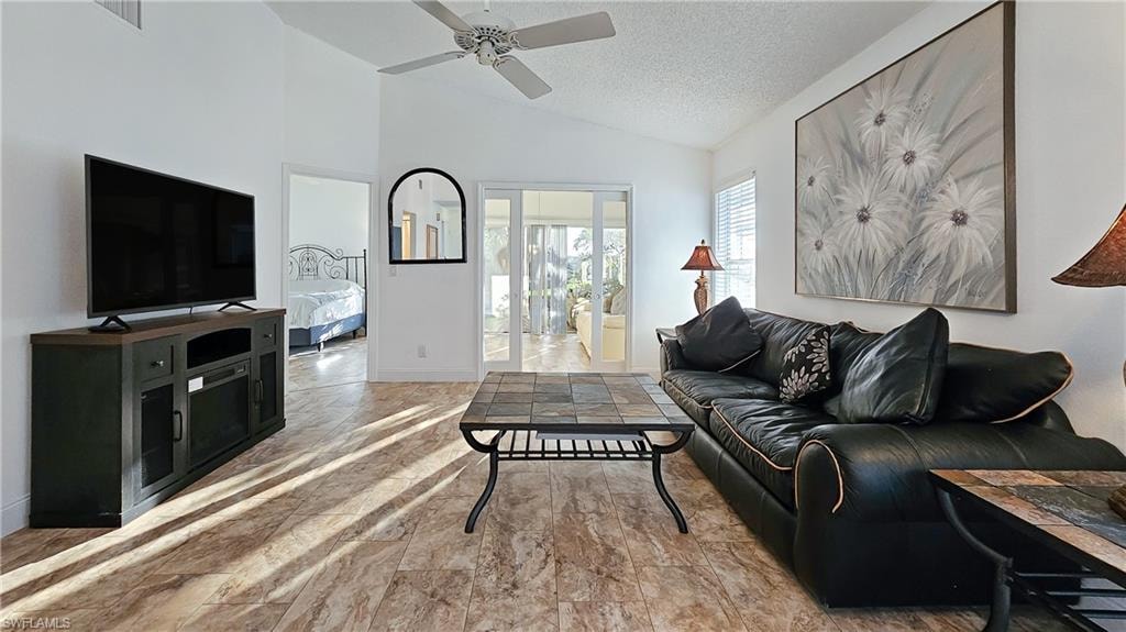 Living room featuring a textured ceiling, a ceiling fan, and high vaulted ceiling