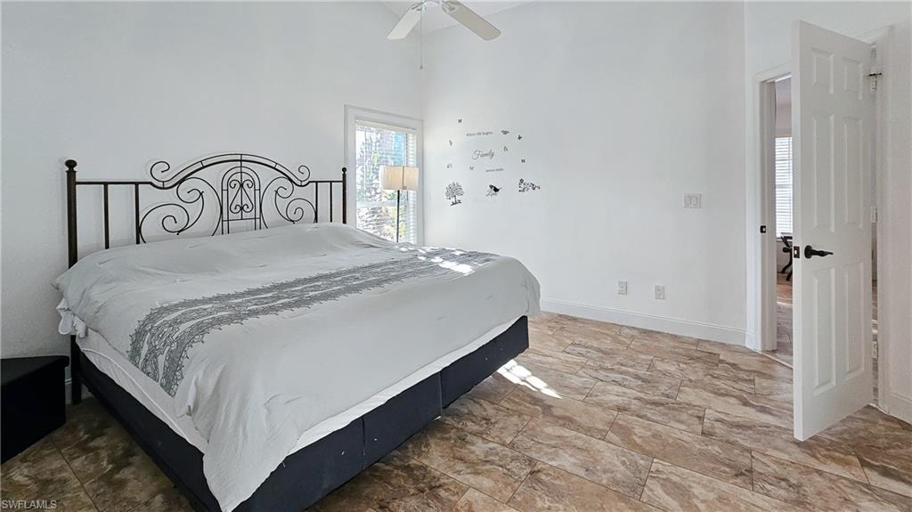 Bedroom with ceiling fan and light stone finish flooring
