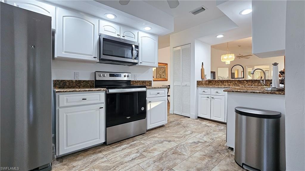 Kitchen with appliances with stainless steel finishes, white cabinetry, dark stone counters, ceiling fan, and recessed lighting