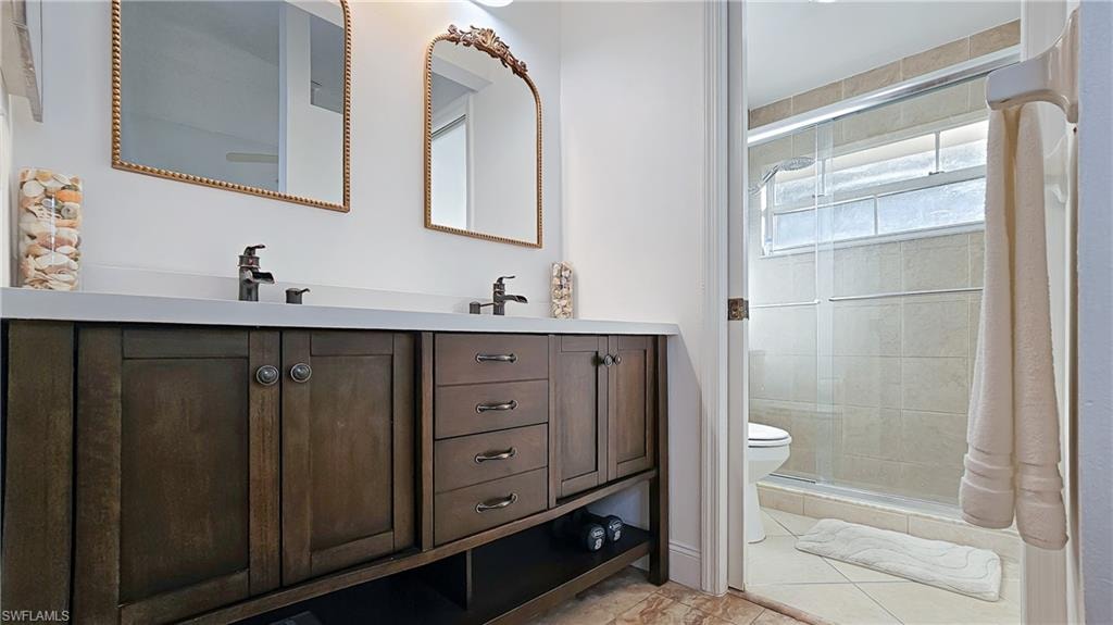 Full bathroom featuring double vanity, a stall shower, and light tile patterned floors