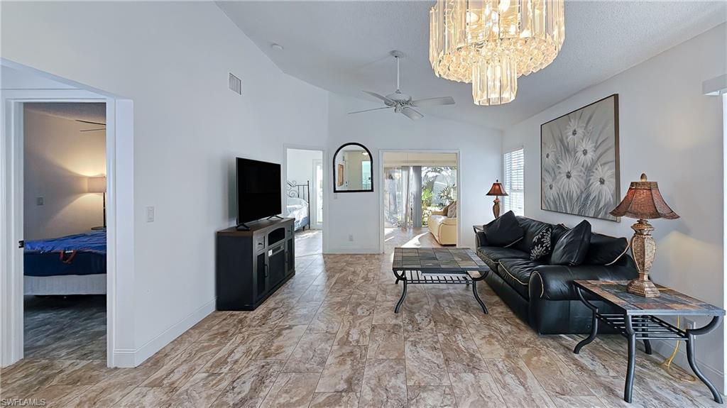 Living room with a ceiling fan, a chandelier, and high vaulted ceiling
