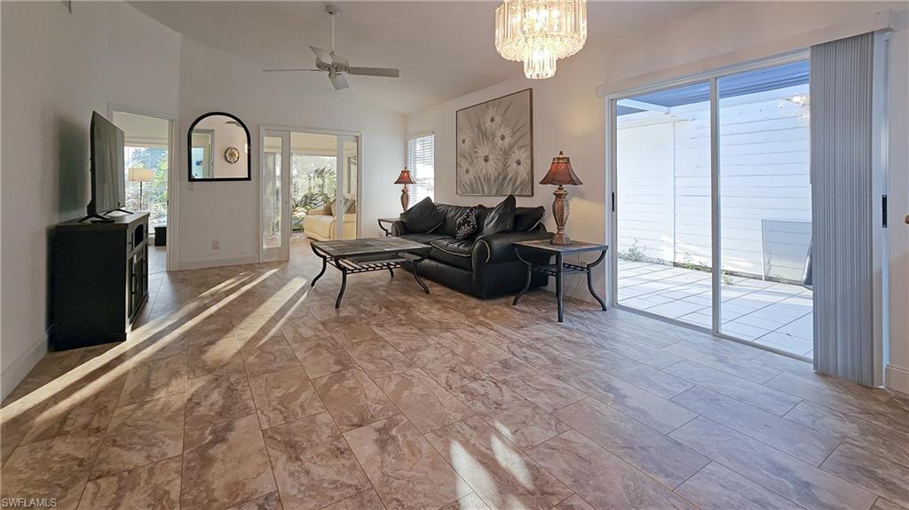 Living room featuring vaulted ceiling, plenty of natural light, a ceiling fan, and a chandelier
