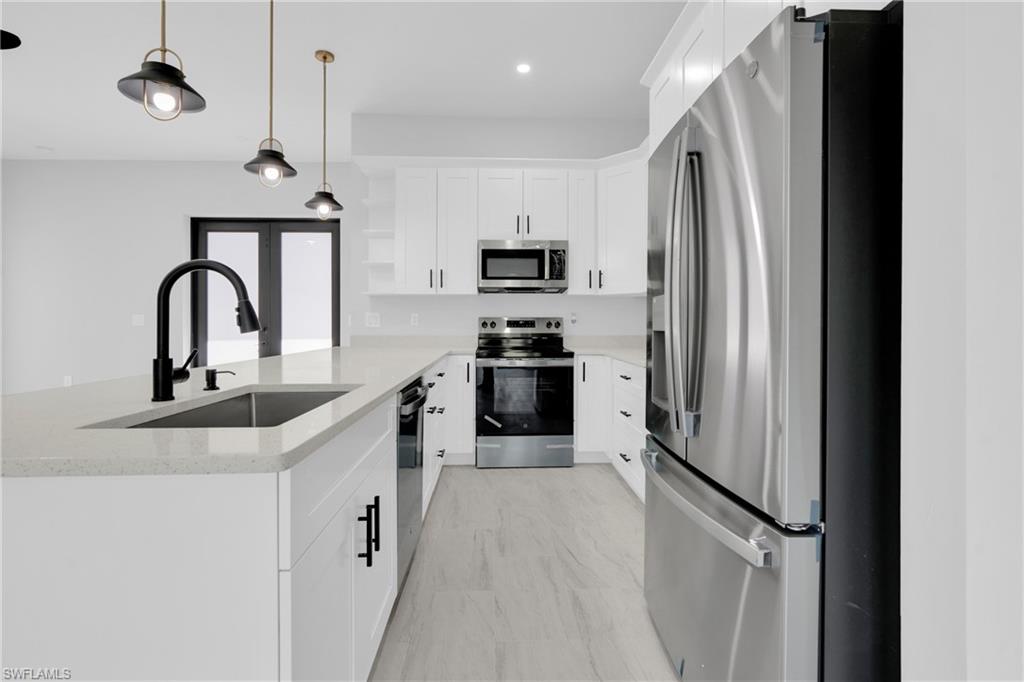 Kitchen featuring open shelves, stainless steel appliances, pendant lighting, a peninsula, and white cabinetry