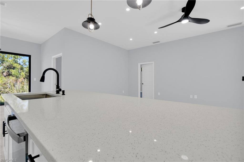 Kitchen with light stone countertops, recessed lighting, decorative light fixtures, and a ceiling fan