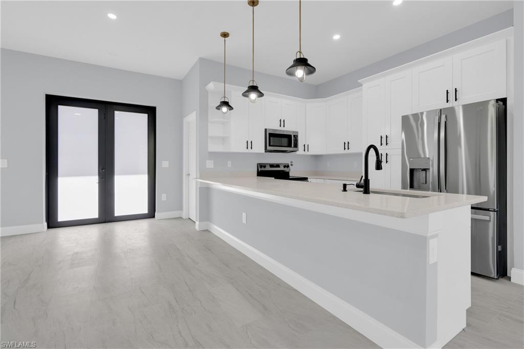 Kitchen with appliances with stainless steel finishes, white cabinetry, pendant lighting, a peninsula, and recessed lighting