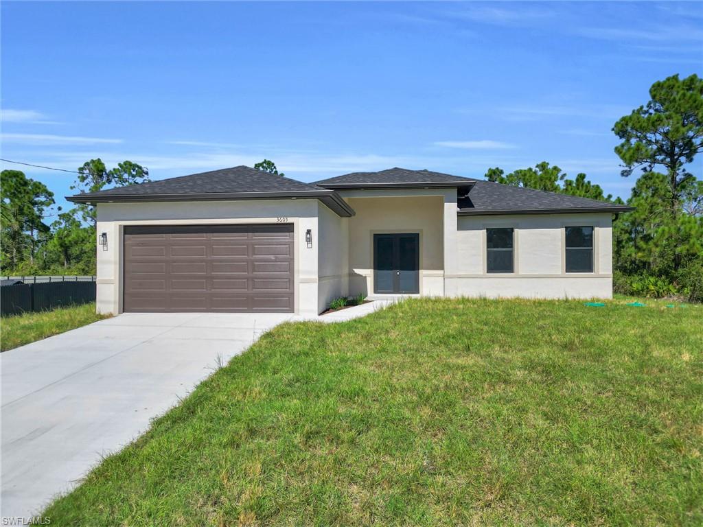 Prairie-style house with stucco siding, driveway, a front lawn, a garage, and roof with shingles