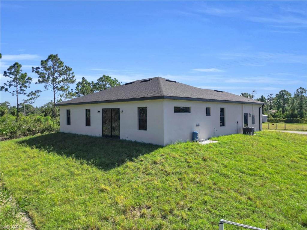 Back of house featuring stucco siding and a yard