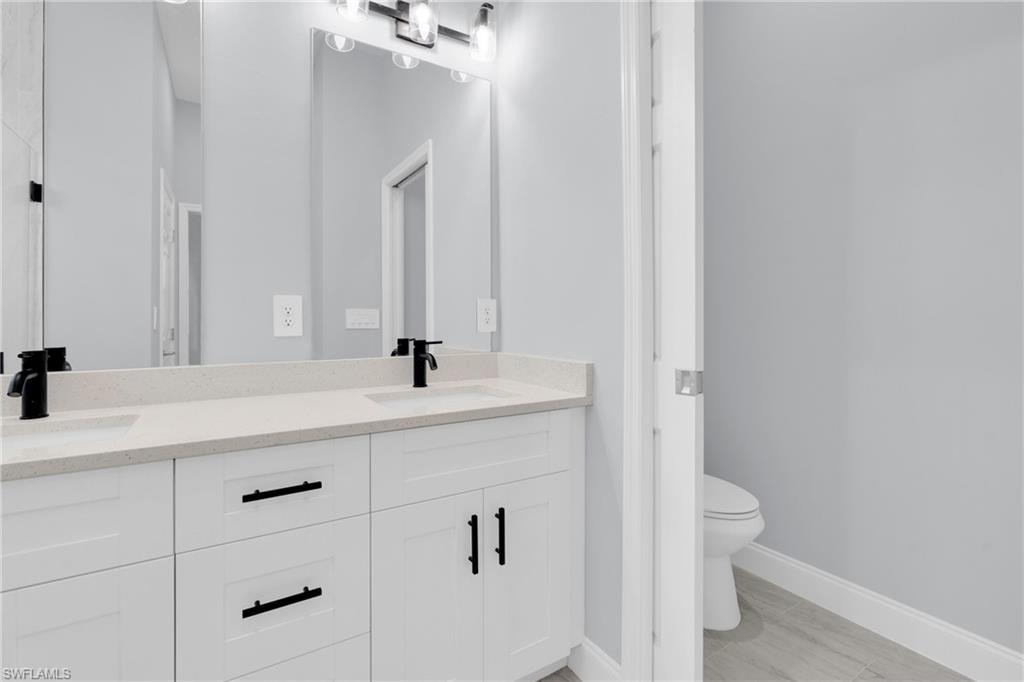 Bathroom with double vanity and light wood-type flooring