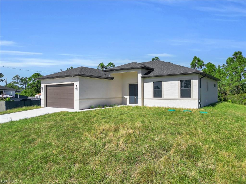 Prairie-style house featuring a front lawn, stucco siding, driveway, and an attached garage