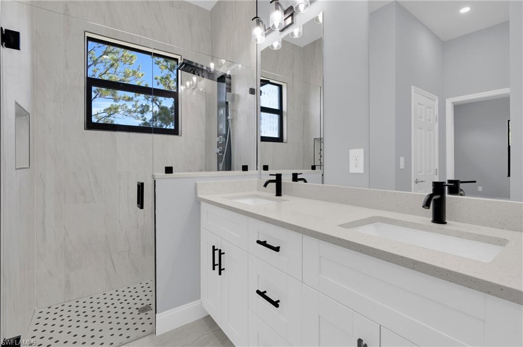 Full bathroom with double vanity and a marble finish shower