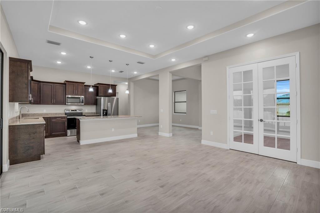 Kitchen featuring hanging light fixtures, a kitchen island, dark brown cabinets, stainless steel appliances, and open floor plan