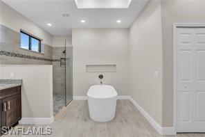 Bathroom featuring a freestanding tub, a shower stall, vanity, light wood-style flooring, and recessed lighting