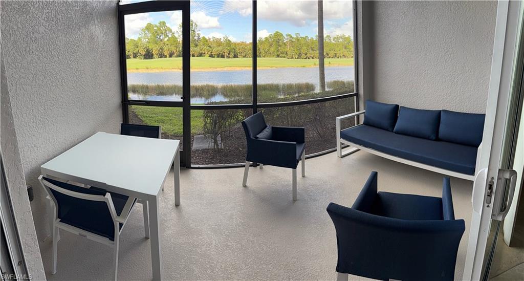 Sunroom featuring a water view, view of wooded area, and plenty of natural light