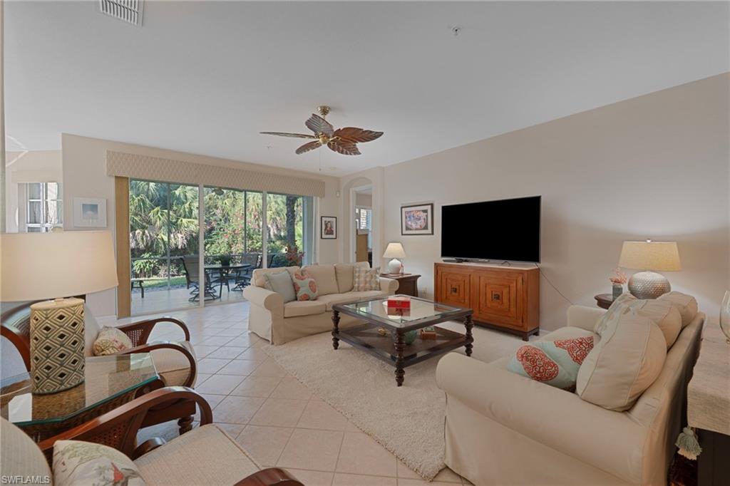 Living area featuring tile patterned floors, a ceiling fan, and arched walkways
