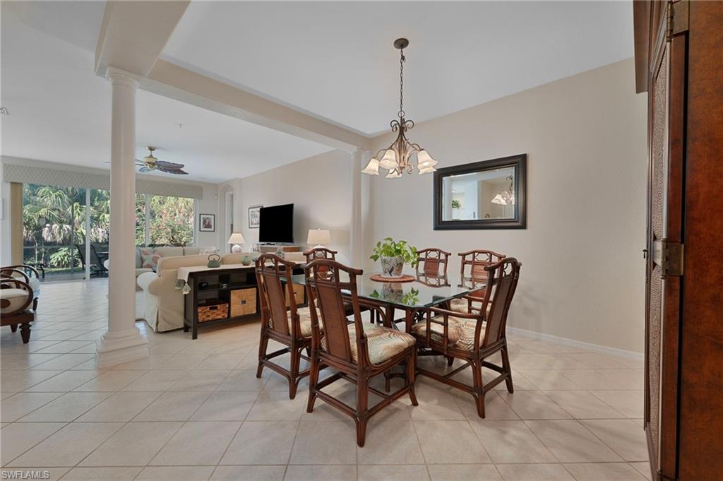 Dining space featuring decorative columns, light tile patterned flooring, a ceiling fan, and a chandelier