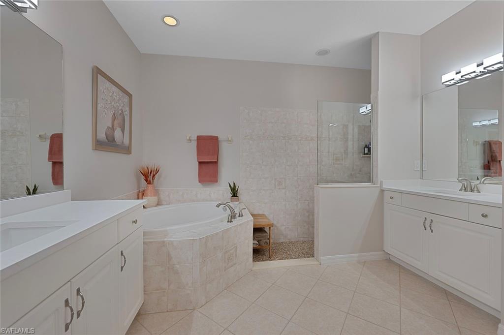 Bathroom featuring two vanities, a garden tub, walk in shower, and light tile patterned flooring