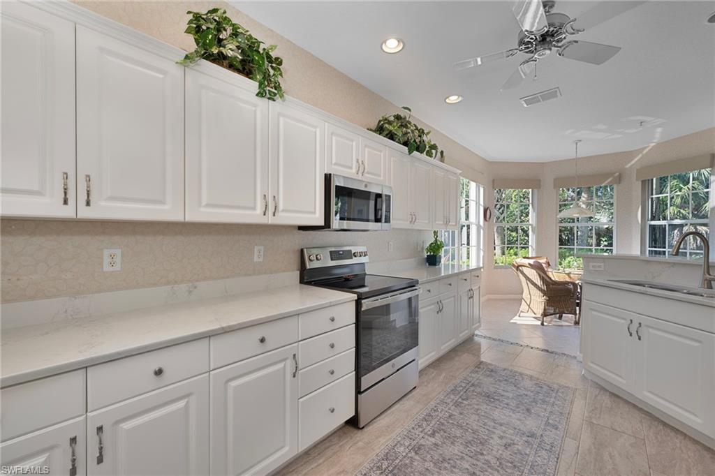Kitchen featuring stainless steel appliances, white cabinetry, recessed lighting, a ceiling fan, and light stone countertops