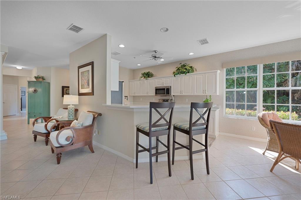 Kitchen with a breakfast bar, light countertops, white cabinets, light tile patterned floors, and appliances with stainless steel finishes