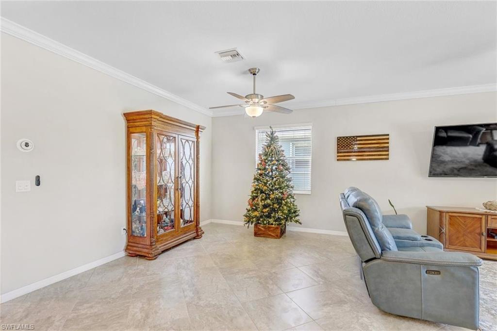 Living area featuring ornamental molding, a ceiling fan, and tile patterned floors
