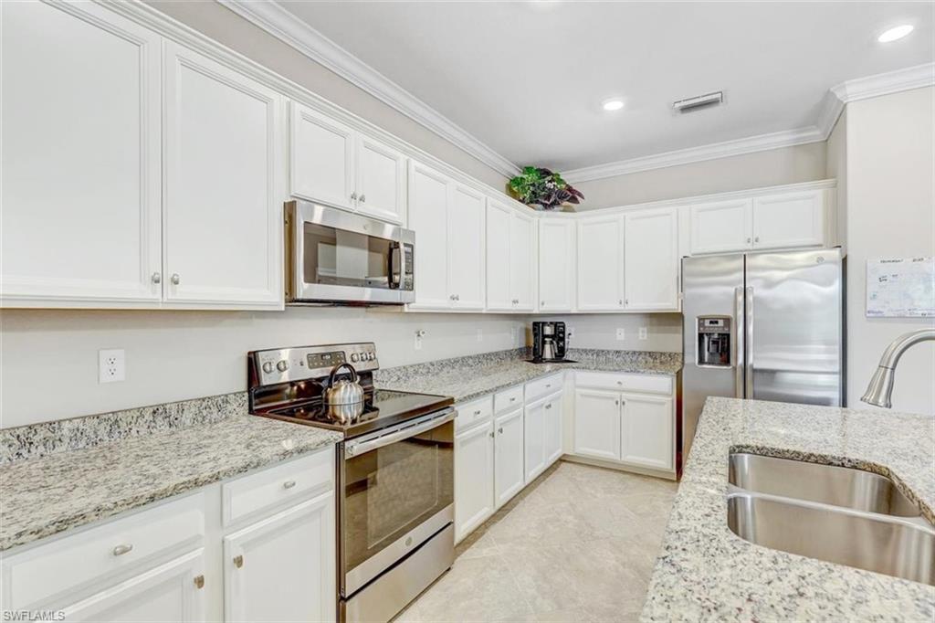 Kitchen with stainless steel appliances, crown molding, white cabinetry, light stone countertops, and recessed lighting