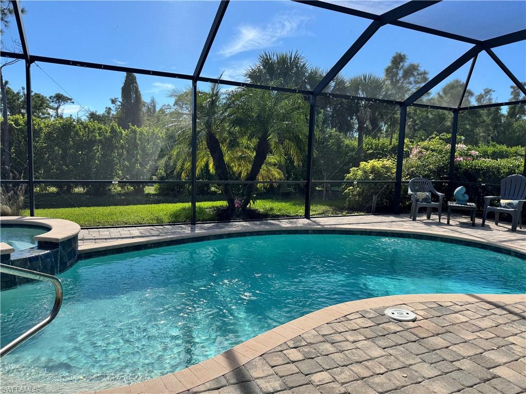 View of pool featuring a sunroom, a lanai, a pool with connected hot tub, and a patio area