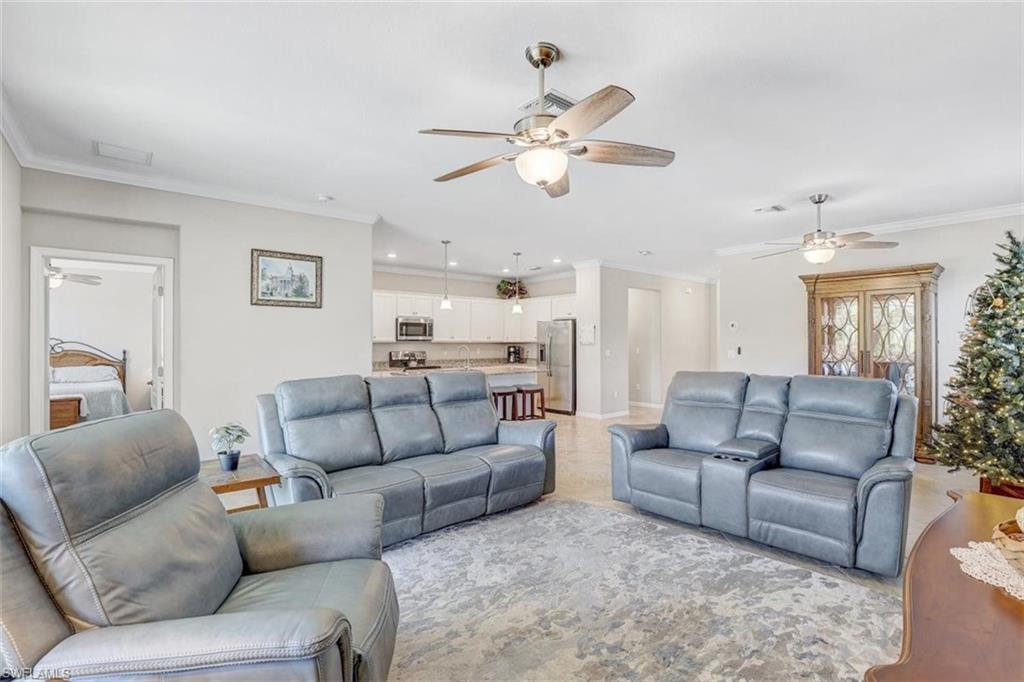 Living area with a ceiling fan, ornamental molding, and recessed lighting