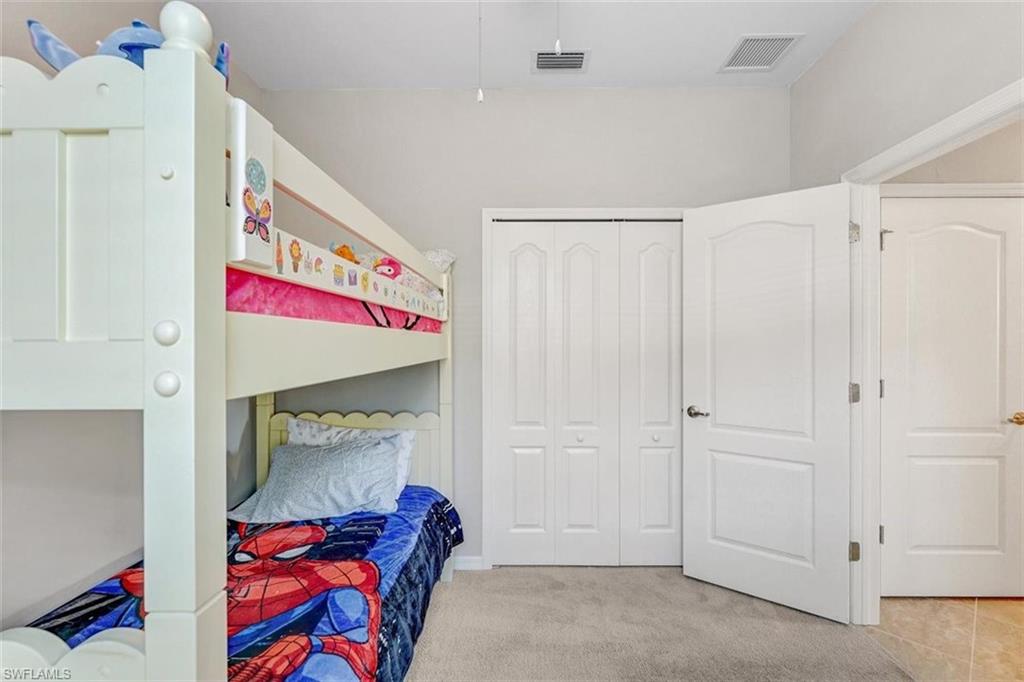 Bedroom with light colored carpet and a closet