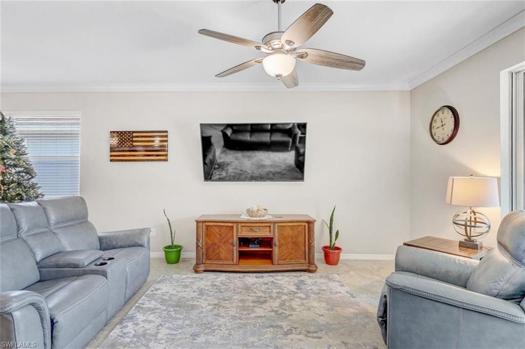 Carpeted living area with crown molding and a ceiling fan