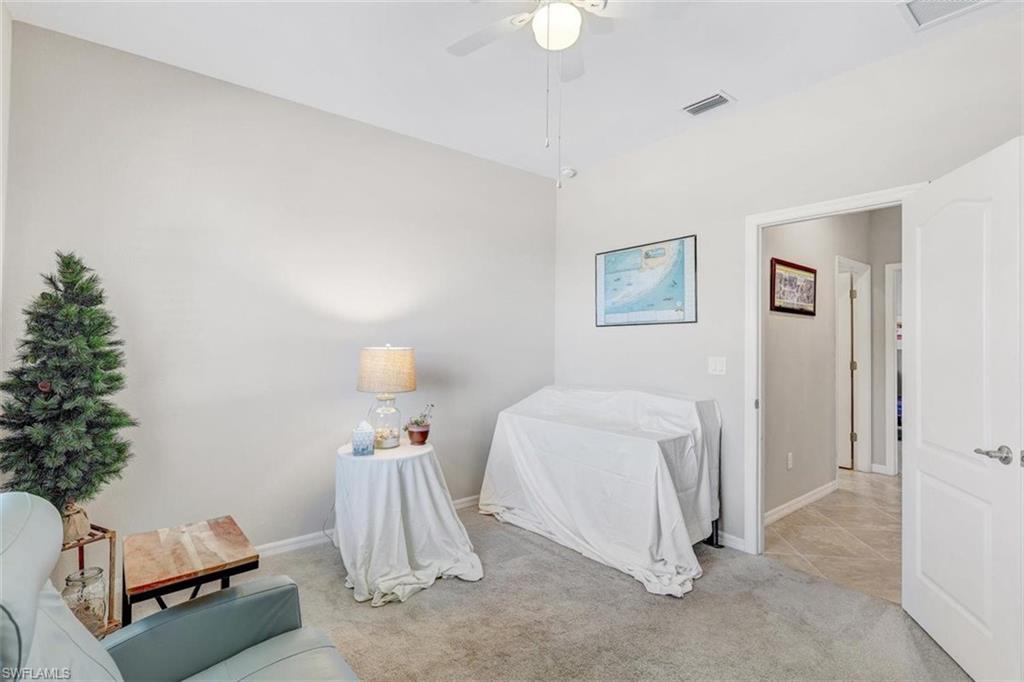 Carpeted bedroom featuring a ceiling fan and tile patterned floors