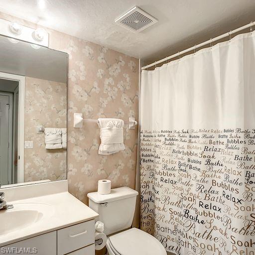 Full bathroom with wallpapered walls, a shower with curtain, and vanity