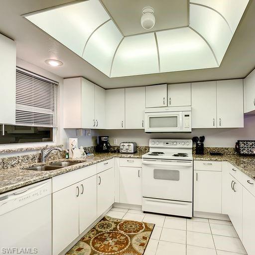 Kitchen with white appliances, light tile patterned floors, and white cabinets