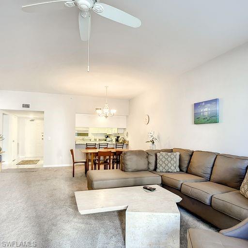 Carpeted living room with a chandelier and ceiling fan
