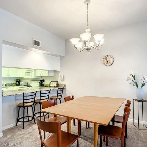 Dining area with a chandelier and light carpet