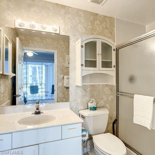 Full bathroom featuring wallpapered walls, a stall shower, and vanity
