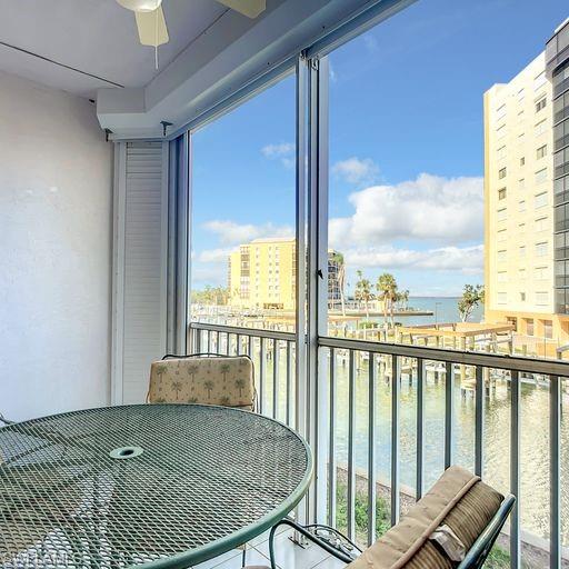 Balcony featuring a water view, a sunroom, and a ceiling fan