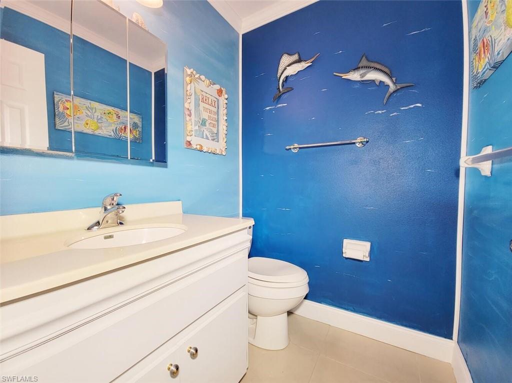 Half bathroom with vanity, light tile patterned flooring, and crown molding
